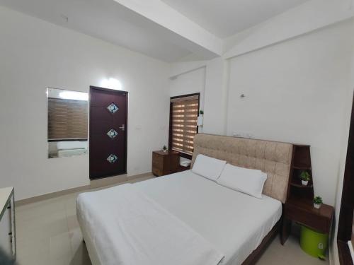 a bedroom with a white bed and a window at Pali homes in Kottayam