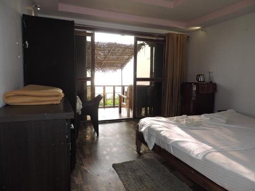 a bedroom with a bed and a desk and a balcony at Fisherman Cove Agonda in Canacona