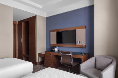 a hotel room with a bed and a desk and a tv at Four Points by Sheraton Izmir in Izmir