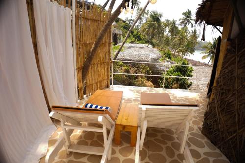a balcony with two chairs and a table on a porch at Nest By Craftels, Goa in Cola