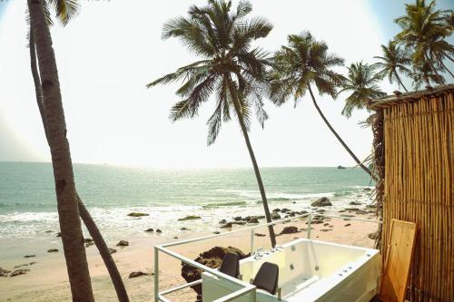 a bath tub sitting on a beach with palm trees at Nest By Craftels, Goa in Cola