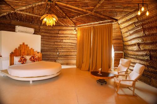a bedroom with a bed and a table and chairs at Nest By Craftels, Goa in Cola