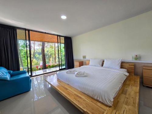 a bedroom with a large bed and a large window at Puprai Tarnnarm Resort in Thong Pha Phum