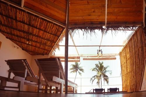 a room with chairs and a large window with palm trees at Nest By Craftels, Goa in Cola