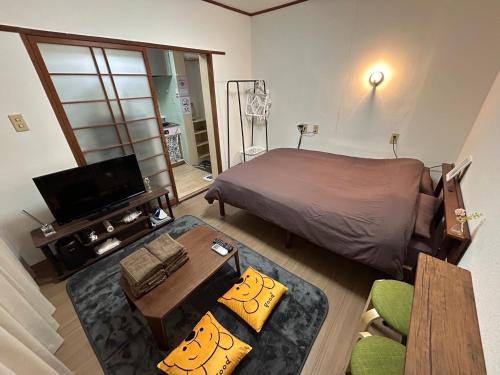 太宰府市にあるGuest House Happy Highness DAZAIFUのベッド、テレビ、ソファのある寝室