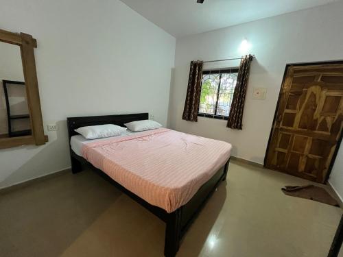 a small bedroom with a bed and a window at God's Gift Morjim in Morjim
