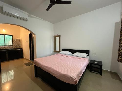 a bedroom with a bed with a pink blanket at God's Gift Morjim in Morjim