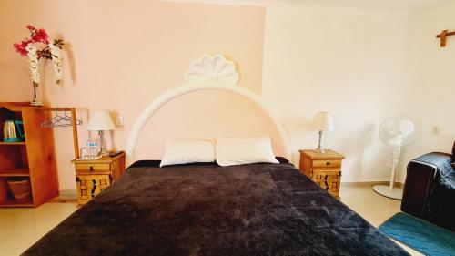 a bedroom with a large bed with a white headboard at HOSTAL DEL ELEFANTE in Tepoztlán