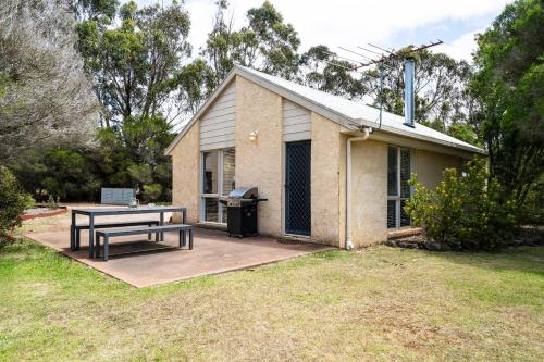 a house with a picnic table in the yard at Bells Beach Cottages in Bellbrae