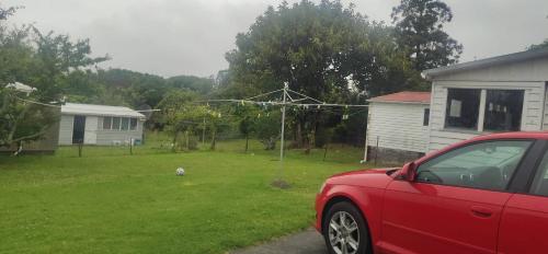 a red car parked in a yard with a dog at 伯爵山庄 in Auckland
