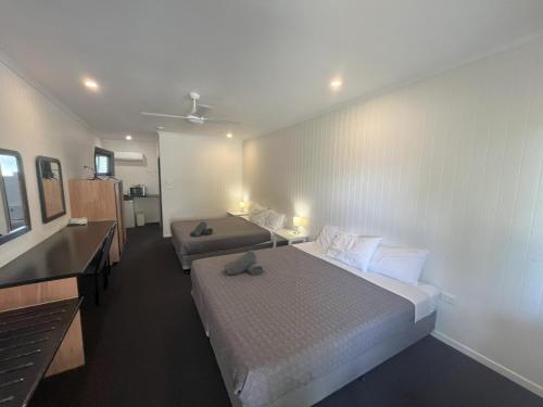 a hotel room with two beds and a desk at Albert Park Motor Inn in Longreach
