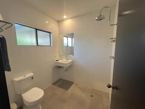 a white bathroom with a toilet and a sink at Albert Park Motor Inn in Longreach