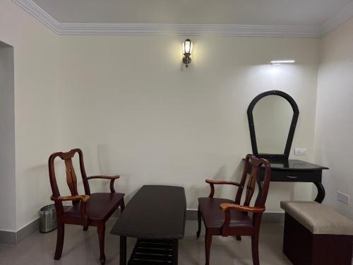 a room with two chairs and a table with a mirror at Malanadu Tourist Home in Hosdrug