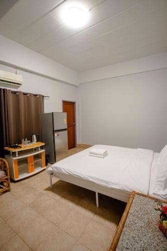 a bedroom with a white bed and a refrigerator at Mitr Inn HuaHin Beach หาดหัวหิน in Hua Hin
