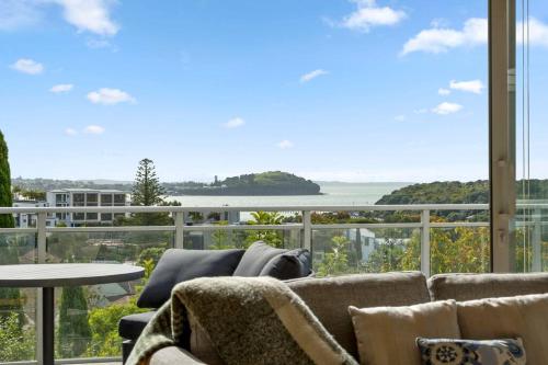 a living room with a couch and a view of the ocean at Welcome to Luxury Living in CBD Near Mission Bay in Auckland