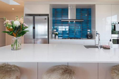 a kitchen with a white counter with a vase of flowers at Welcome to Luxury Living in CBD Near Mission Bay in Auckland