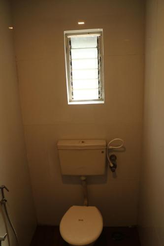 a small bathroom with a toilet and a window at Hotel Geetanjali St Bus Stand Panvel in Panvel