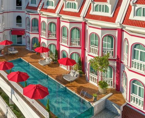 an aerial view of a building with a pool and red umbrellas at Hotel Midtown Ratsada in Phuket Town