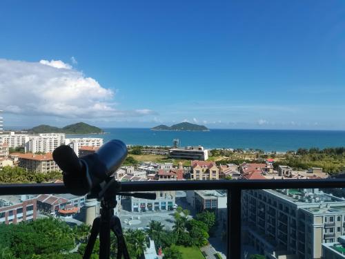 a view of the ocean from a room with a telescope at Hainan Peninsula Sunshine Seaview Apartment Shenzhou Peninsula Branch in Wanning