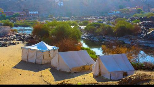 three tents sitting on the side of a river at ASSINGAR camp in Jazīrat Suhayl
