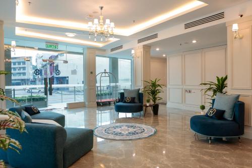 a lobby with two blue chairs and a chandelier at The Host Hotel in Ipoh
