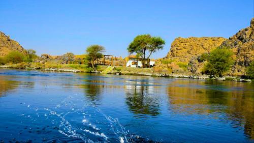 a body of water with a house in the background at ASSINGAR camp in Jazīrat Suhayl