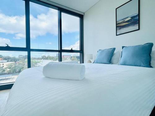 a white bed in a room with a large window at Modern stylish 3 bedroom condo - Parking, Gym, Pool in Sydney