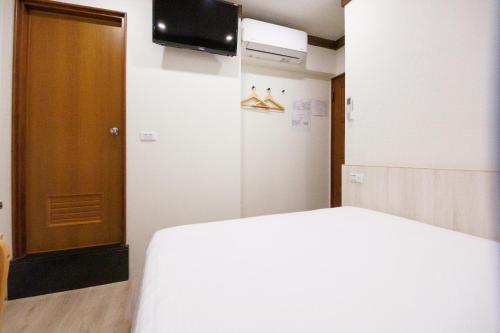 a room with a bed and a television and a door at 許家古宅 4-6人包棟民宿 in Tainan