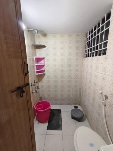 a bathroom with a toilet and a pink bucket at ZTRIO Vacations in Chikmagalūr