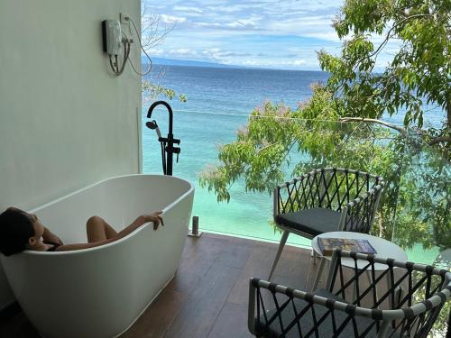 a little girl sitting in a bath tub with a view of the ocean at The French Villa-Santander Cebu in Santander