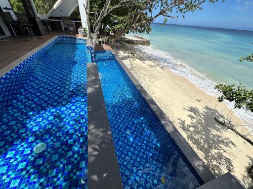 a swimming pool with blue rocks next to the beach at The French Villa-Santander Cebu in Santander