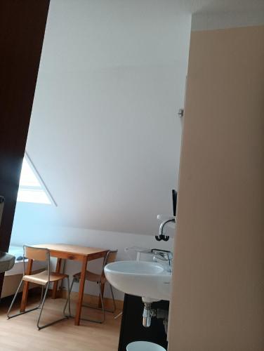 a bathroom with a white sink and a table at Pension Urbanstraße 46 in Stuttgart