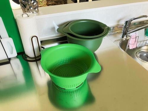 two green buckets sitting on a counter next to a sink at Casa Kikuchi in Kikuchi