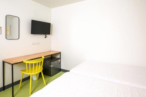 a bedroom with a desk and a bed and a yellow chair at Hello my friend in Bang Bua Thong Railway Station