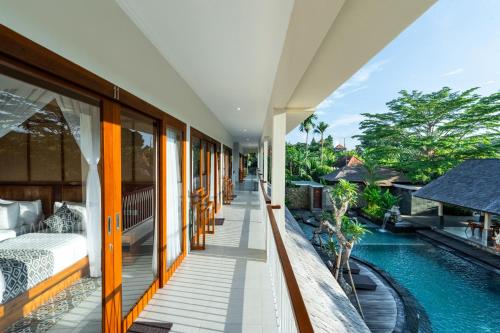a balcony of a villa with a bed and a swimming pool at Puri Andong Villa in Ubud
