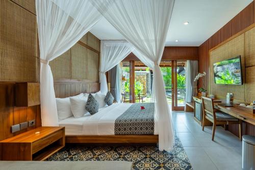 a bedroom with a bed with curtains and a desk at Puri Andong Villa in Ubud