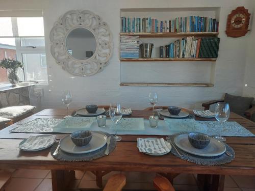 a wooden table with plates and glasses and a mirror at Lieflappie❤ in Stilbaai