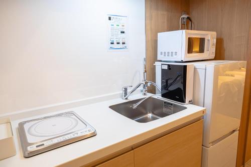 a kitchen with a sink and a microwave at GOLD STAY Nagoya Sakae ゴールドステイ名古屋栄 in Nagoya