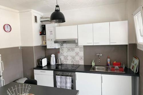 une cuisine avec des armoires blanches et un évier dans l'établissement Studio agréable & lumineux proche hôpital Pasteur, à Nice