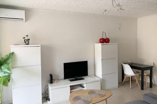 - un salon blanc avec une télévision et une table dans l'établissement Studio agréable & lumineux proche hôpital Pasteur, à Nice