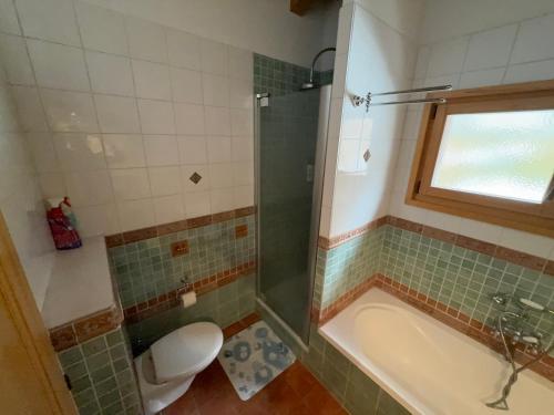 a bathroom with a tub and a toilet and a window at Grand chalet au centre in Anzère