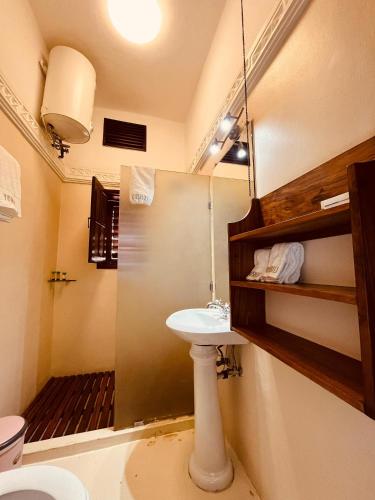 a bathroom with a sink and a toilet and a mirror at Yushili Hotel Kampala in Kampala