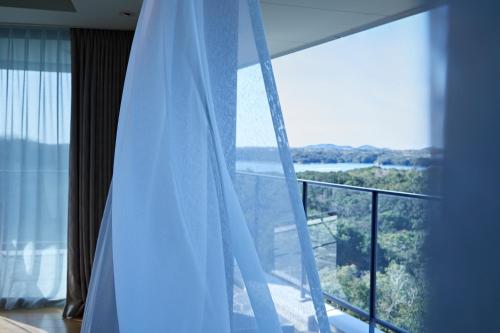 a room with a window with a view of a balcony at Shima Kanko Hotel The Bay Suites in Shima