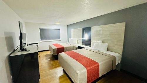 a hotel room with two beds and a flat screen tv at Evergreen Inn & Suites Portland in Portland