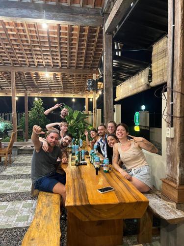 a group of people sitting around a wooden table at OKU Guest House in Giri