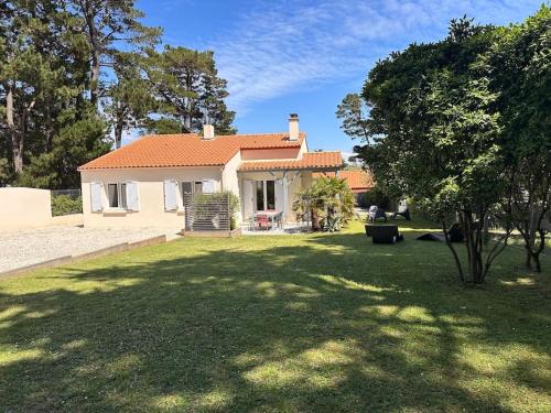 a small house in a yard with a tree at Maison Familiale bord de mer in Préfailles