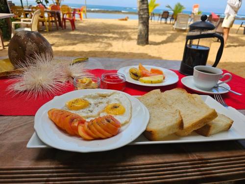 a plate of eggs and bread and toast on a table at the beach at Paradise Bay in Beruwala