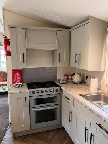 a kitchen with white cabinets and a stove top oven at Lazeeedays on Mersea Island in Colchester