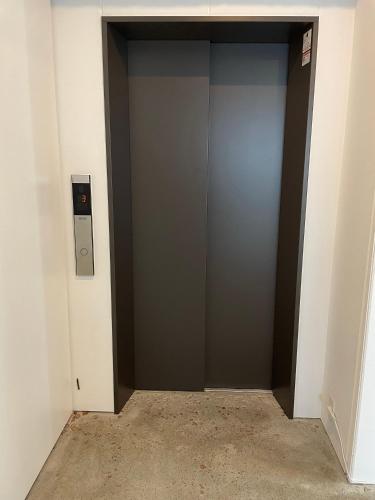 an elevator in a building with a gray door at まえばしガレリアArt residence & Hotel in Maebashi
