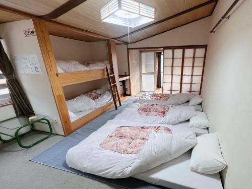a room with three bunk beds in it at AKANE Hostel あかね天然温泉旅館 in Yuzawa
